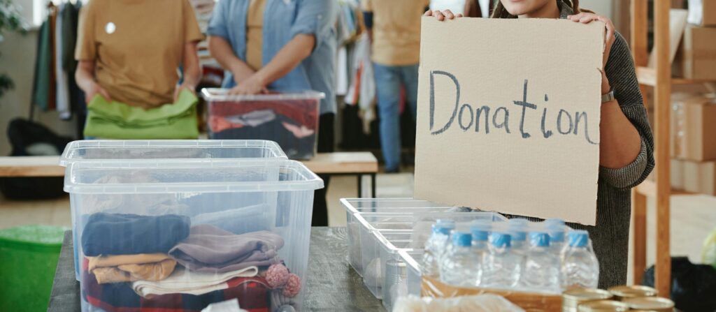 Group of volunteers organizing clothing and water donations indoors.